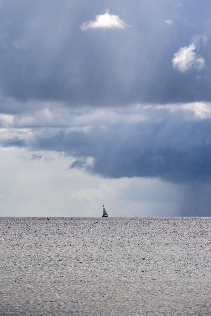 Segelboot auf der Ostsee bei dunklem Himmel und Wolken.