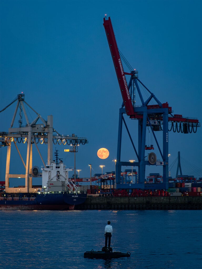 Großer Hafenkran bei Nacht mit Mond im Hintergrund.